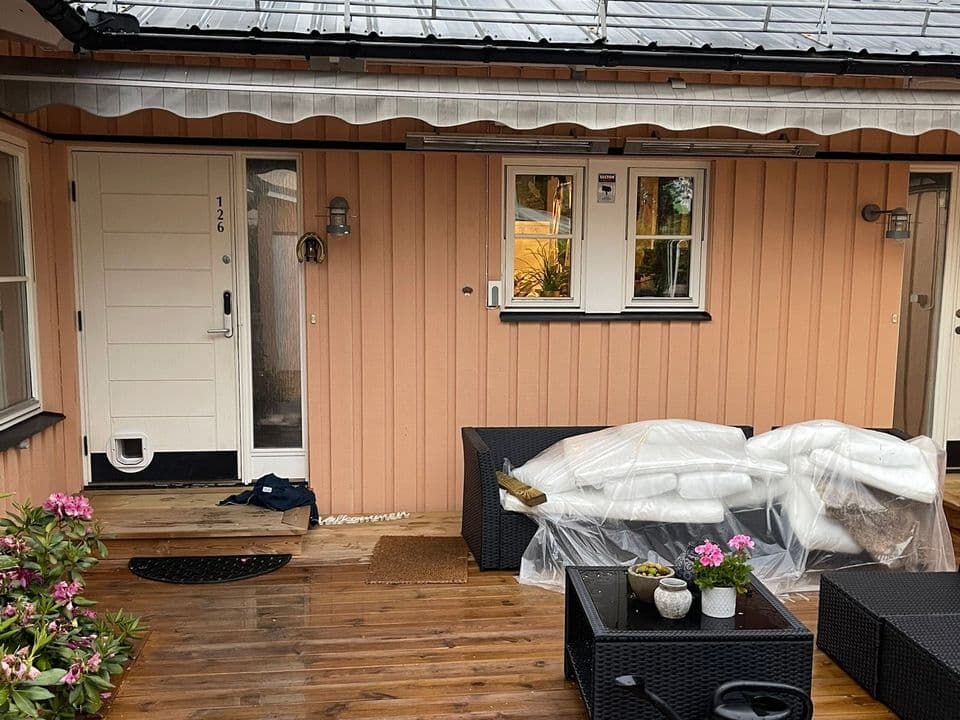 Nymålad laxrosa fasad och vit dörr vid en trädäcksaltan
